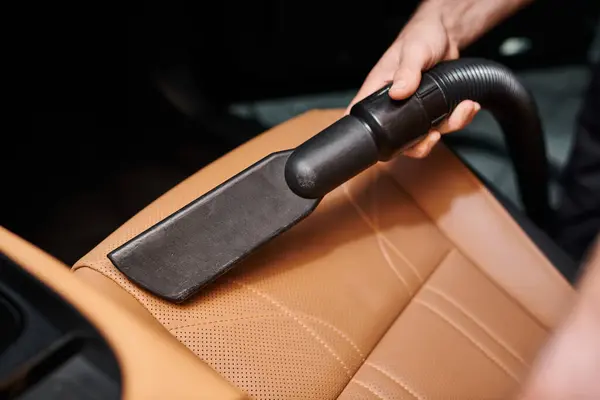 Cropped view of hard working serviceman using manual vacuum cleaner on seat in car in garage — Stock Photo