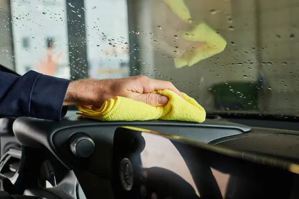 Cropped view of dedicated professional serviceman using yellow rag to clean modern car in garage — Stock Photo