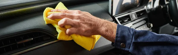 Cropped view of hard working serviceman in uniform cleaning glove compartment of car with rag — Stock Photo