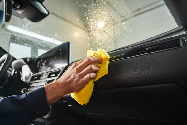 Cropped view of hard working professional in uniform cleaning glove compartment with yellow rag — Stock Photo