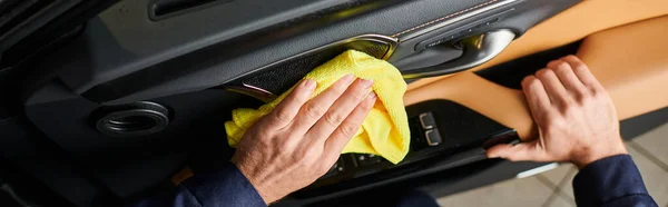 Cropped view of hard working specialist in comfortable uniform cleaning car door with rag, banner — Stock Photo