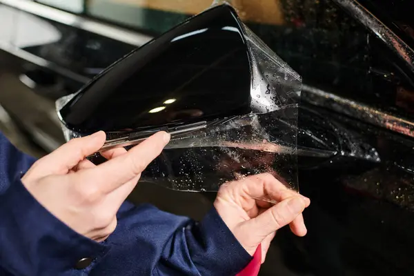 Обрізаний вид на працьовитого військовослужбовця, який наносить захисну фольгу на дзеркало чорного автомобіля — стокове фото