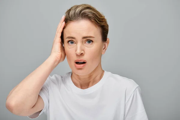 Appealing surprised blonde woman with collected hair and contact lenses looking straight at camera — Stock Photo
