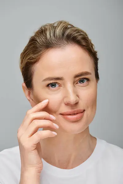 Joyful good looking woman with contact lenses and blonde hair looking at camera on gray backdrop — Stock Photo