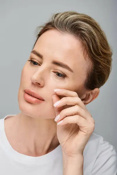 Beautiful blonde woman with contact lenses and collected hair looking away on gray backdrop — Stock Photo