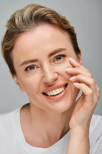 Joyous good looking woman with contact lenses and blonde hair looking at camera on gray backdrop — Stock Photo