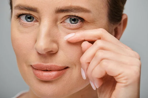 Joyous good looking woman with contact lenses and blonde hair looking at camera on gray backdrop — Stock Photo