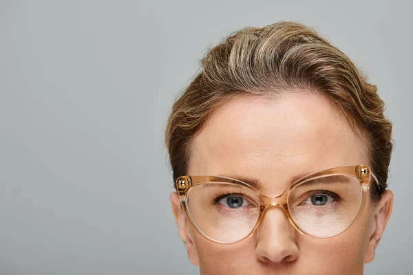 Gut aussehende blonde weibliche Modell mit Brille und gesammelten Haaren in posieren auf grauem Hintergrund — Stockfoto