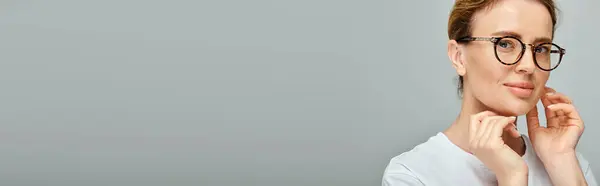 Joyful attractive woman with blonde hair with glasses smiling at camera on gray background, banner — Stock Photo
