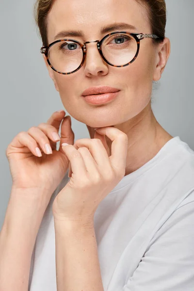 Joyous attractive woman with blonde hair with glasses smiling happily at camera on gray background — Stock Photo