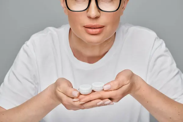Cropped view of woman in casual attire wearing glasses and holding contact lenses in hands — Stock Photo