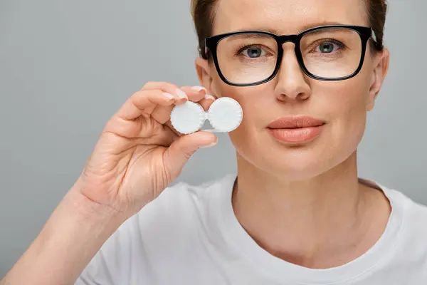 Happy appealing woman with blonde hair and glasses holding contact lenses and looking at camera — Stock Photo