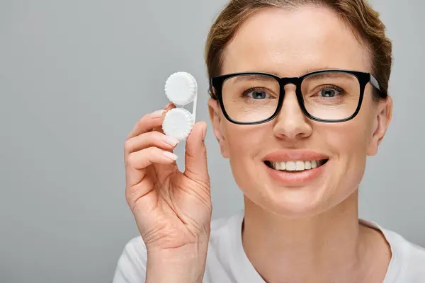 Joyful appealing woman with blonde hair and glasses holding contact lenses and looking at camera — Stock Photo