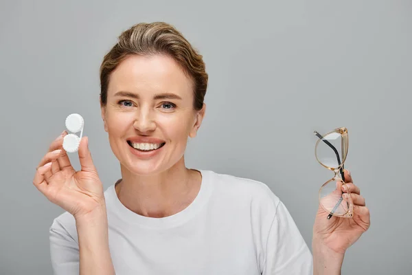 Joyous appealing woman with blonde hair and glasses holding contact lenses and looking at camera — Stock Photo