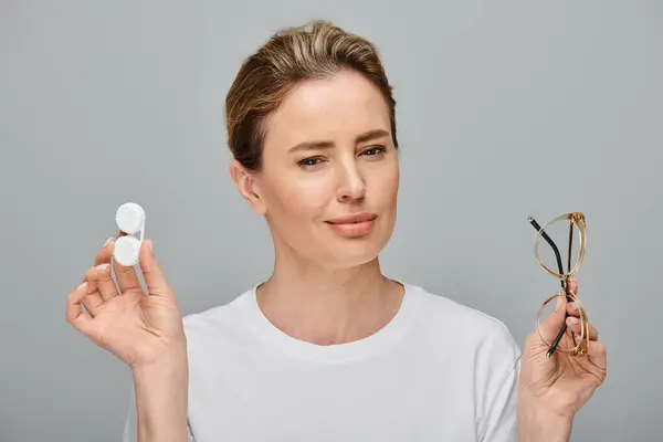 Cheerful appealing woman with blonde hair and glasses holding contact lenses and looking at camera — Stock Photo