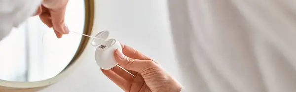 Cropped view of woman in cozy bathrobe cleaning her teeth with dental floss in bathroom, banner — Stock Photo