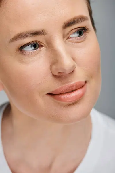 Retrato de mulher bonita com loira coletada cabelo posando em fundo cinza e olhando para longe — Fotografia de Stock