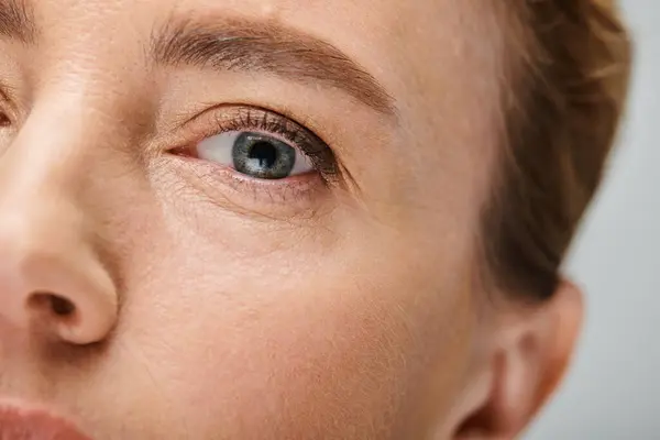 Крупным планом привлекательная женщина со светлыми волосами смотрит на камеру с контактным линзой на глазу — стоковое фото
