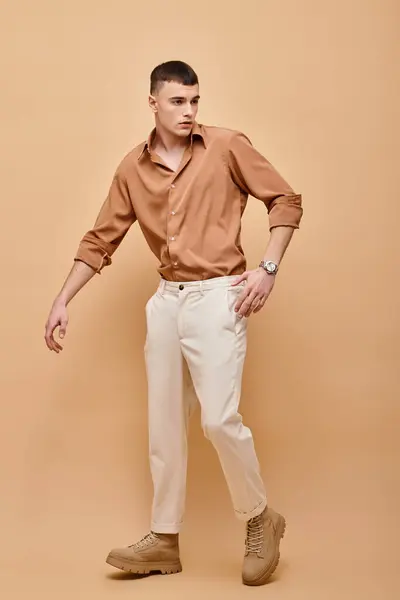 Immagine a figura intera di giovane in camicia beige, pantaloni e stivali in posa su sfondo beige — Foto stock