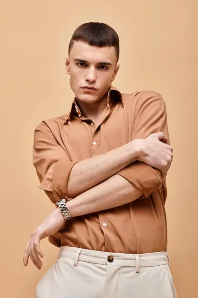 Retrato de hombre guapo con estilo en camisa beige con las manos cruzadas sobre fondo beige - foto de stock