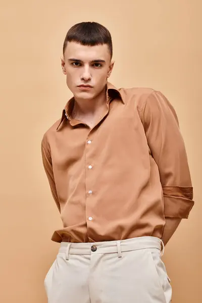 Ritratto di bell'uomo in camicia beige con le mani sopra la schiena su sfondo beige — Foto stock