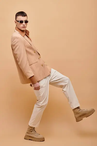 Fashion portrait of man in beige jacket, shirt, pants and boots posing on beige background, banner — Foto stock