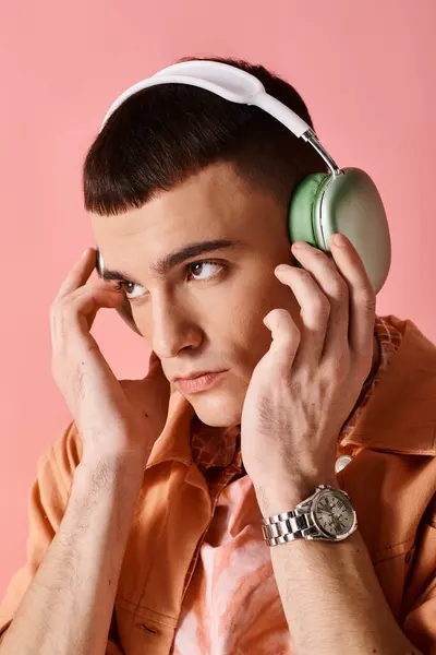 Portrait pf homme élégant avec écouteurs sans fil écouter de la musique sur fond rose — Photo de stock