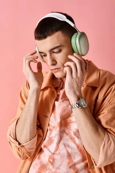 Handsome man with wireless headphones listening to music on pink background looking down — Stock Photo