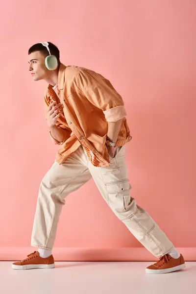 Foto completa do homem usando fones de ouvido sem fio dançando à música no fundo rosa — Fotografia de Stock