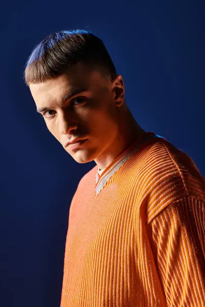 Portrait of young stylish man in orange shirt looking at camera on dark blue background — Stock Photo