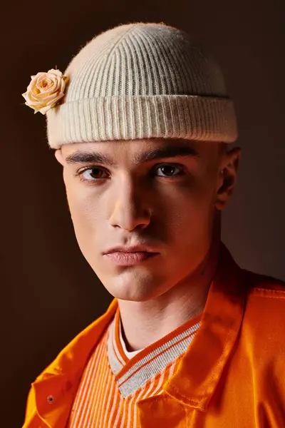 Portrait of stylish man in orange outfit wearing beige beanie with flower looking at camera — Stock Photo