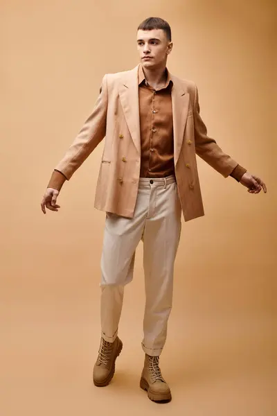 Full length portrait of fashionable man in beige jacket, shirt, pants and boots on beige background — Stock Photo