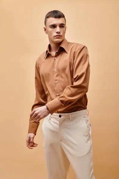 Porträt eines stilvollen, gut aussehenden Mannes im beigen Hemd, der die Hände auf einem pfirsichfarbenen beigen Hintergrund bewegt — Stockfoto