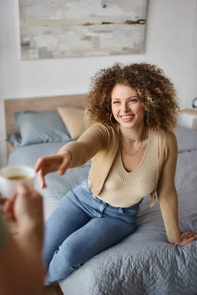 Curly woman smiling woman taking a coffee cup of boyfriends hand, caring and enjoying time at home — Stock Photo
