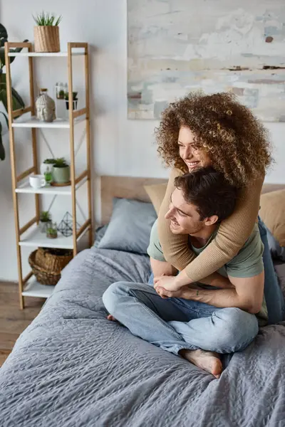 In a cozy embrace, curly young woman and brunette man share a loving moment in bed — Stock Photo