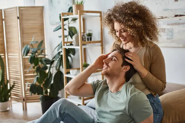 Curly young woman gently massaging boyfriends head smiling together in bedroom — Stock Photo