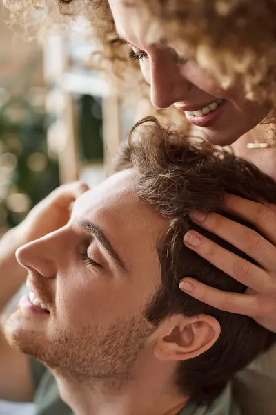 Closeup of curly young woman gently massaging boyfriends head smiling together — Stock Photo