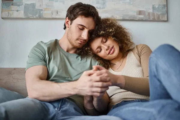 Dans leur chambre confortable, jeune femme bouclée et homme brune partageant un moment de larme et câlin — Photo de stock