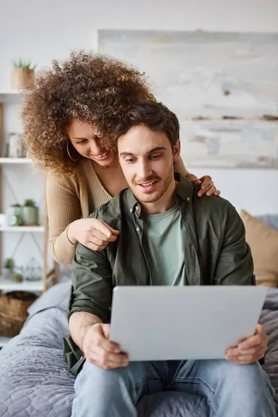 Ricci giovane donna e bruna uomo seduto comodamente con il loro computer portatile, godendo la mattina — Foto stock