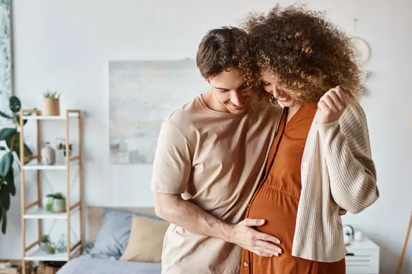 Любящие пары в своей спальне, нежно обнимающиеся, ожидая ребенка, беременная женщина улыбается — стоковое фото