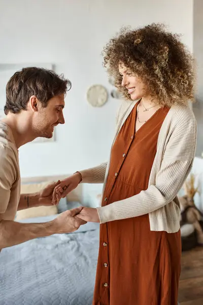 Cheerful man holding his pregnant wife hand and talking to their baby in belly of future mom — Stock Photo