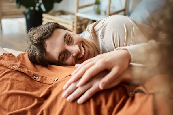 Обрезанный вид беременной женщины с мужем в спальне, лежащий в постели и улыбающийся, мужчина трогательный живот — стоковое фото