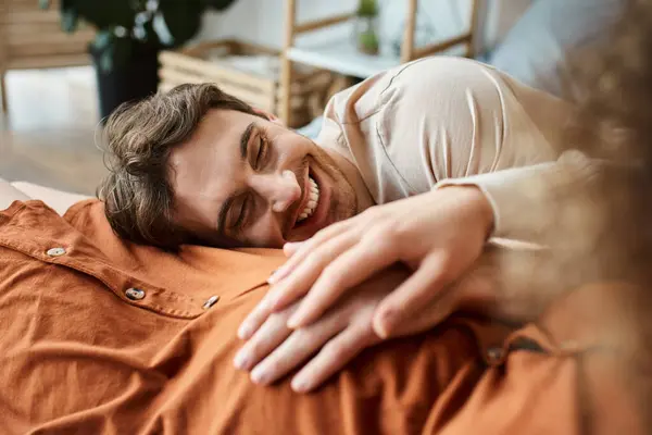 Cropped view of pregnant woman with husband in bedroom, lying in bed and smiling, man touching belly — Stock Photo