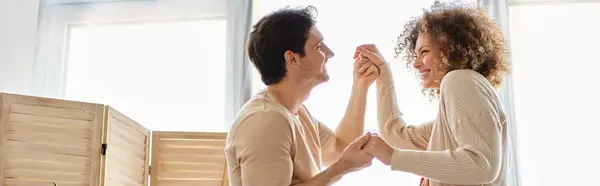 Preciosa pareja joven pasar tiempo juntos en casa bailando cogidos de la mano con sonrisa, pancarta - foto de stock