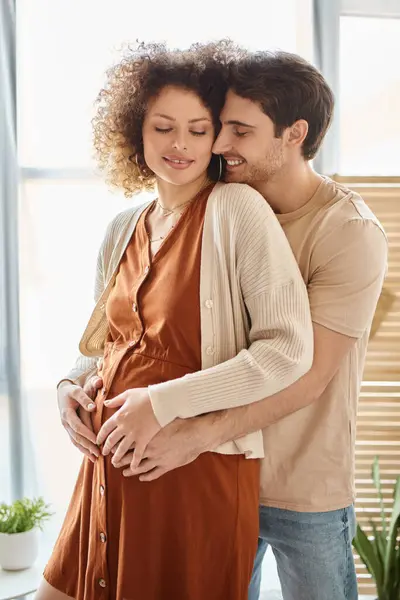 Schöner glücklicher Mann, der seine schwangere Frau von hinten umarmt und zu Hause auf das Baby wartet — Stockfoto