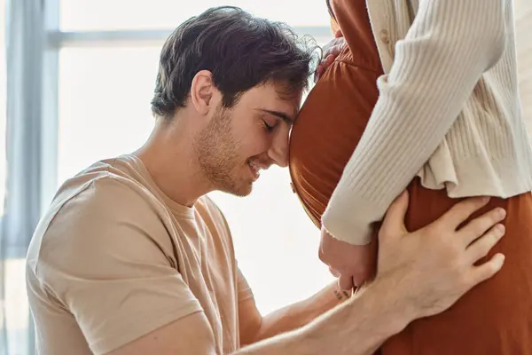 Side view of smiling happy man waiting for baby hugging belly of wife with closed eyes — Stock Photo
