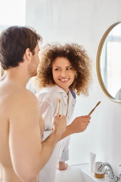 Happy couple in love in bathroom. Young couple laughing while brushing teeth together — Stock Photo