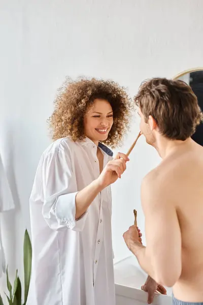 Young happy couple laughing and having fun while brushing teeth together in the morning in bathroom — Stock Photo