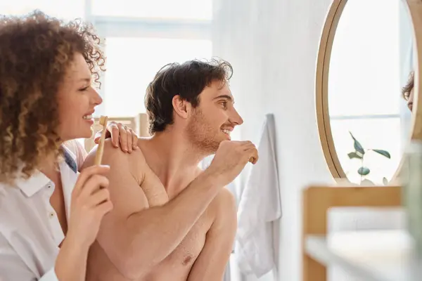 Съемка счастливой пары, сближающейся, когда чистишь зубы в ванной, обнимаешься и смеешься — стоковое фото