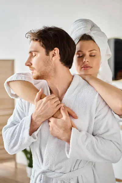 Couple attrayant en peignoirs serrant dans la salle de bain, femme avec serviette sur la tête — Photo de stock